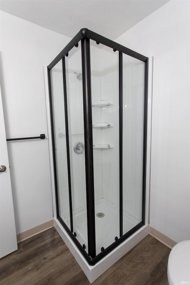 bathroom with toilet, an enclosed shower, and hardwood / wood-style flooring