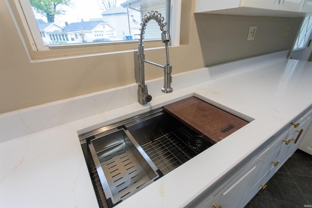 interior details with white cabinets, dark tile patterned flooring, and sink