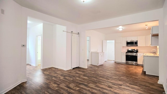 kitchen with stainless steel appliances, a barn door, dark hardwood / wood-style flooring, sink, and white cabinets