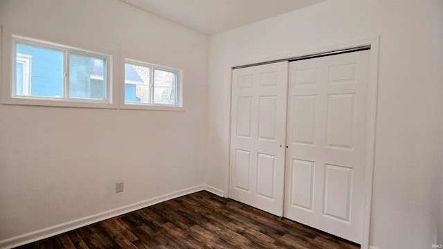 unfurnished bedroom with dark hardwood / wood-style flooring and a closet