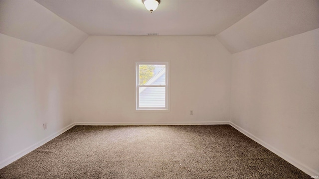 additional living space featuring vaulted ceiling and carpet flooring