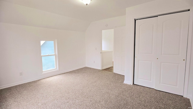 unfurnished bedroom with a closet, lofted ceiling, and carpet floors