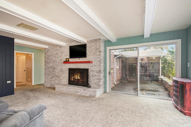 living room with a fireplace, beamed ceiling, and carpet floors