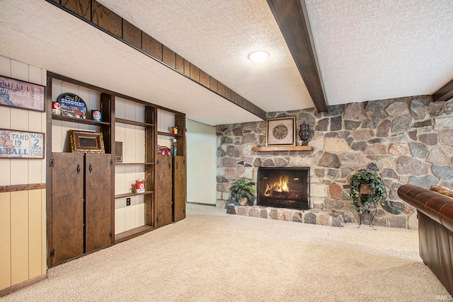 carpeted living room with wood walls, a stone fireplace, and a textured ceiling