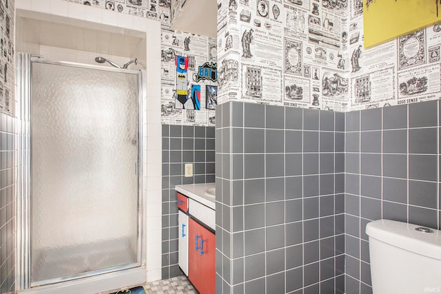 bathroom featuring toilet, vanity, an enclosed shower, and tile walls