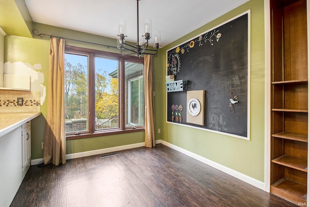 unfurnished dining area with dark hardwood / wood-style flooring and a chandelier