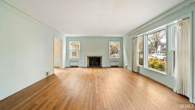 unfurnished living room featuring ornamental molding, light wood-type flooring, and radiator