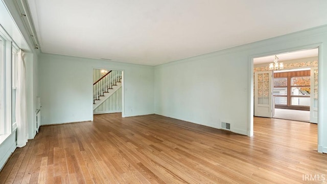 spare room featuring light hardwood / wood-style floors and a notable chandelier