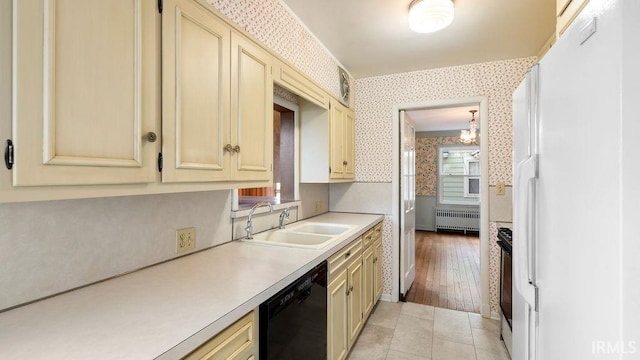 kitchen with black appliances, radiator heating unit, sink, light hardwood / wood-style floors, and cream cabinetry