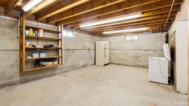 basement with washer / clothes dryer and white refrigerator