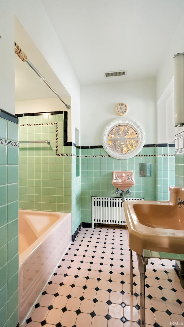 bathroom featuring radiator, a bathing tub, and tile walls