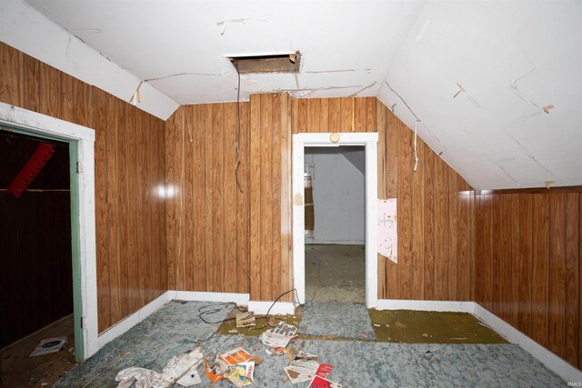 bonus room with wooden walls and vaulted ceiling