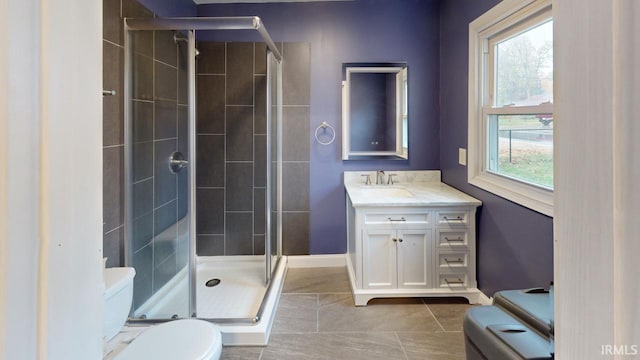 bathroom with tile patterned flooring, a wealth of natural light, vanity, and toilet