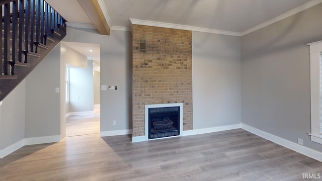 unfurnished living room featuring ornamental molding, a brick fireplace, light hardwood / wood-style floors, and beamed ceiling