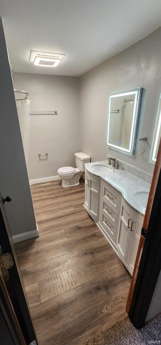 bathroom with hardwood / wood-style floors, vanity, and toilet