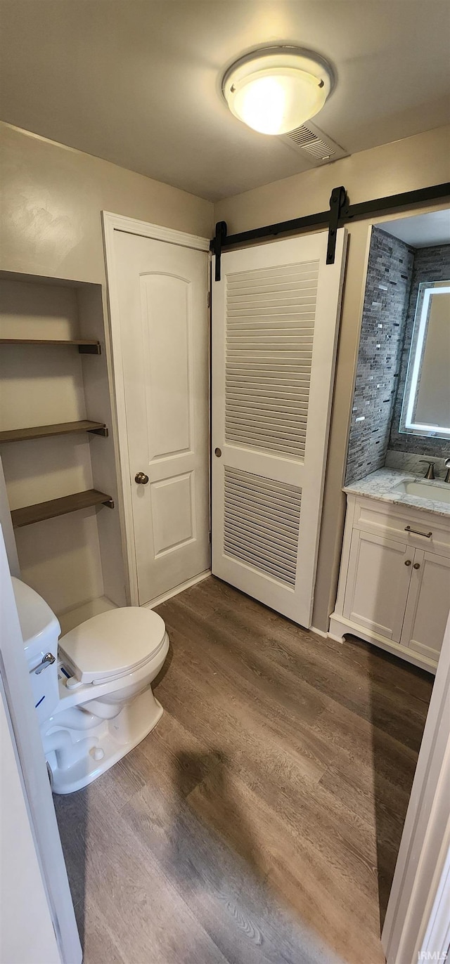 bathroom with toilet, vanity, and hardwood / wood-style flooring