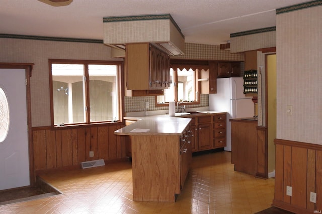 kitchen featuring a wealth of natural light, wooden walls, backsplash, and a center island