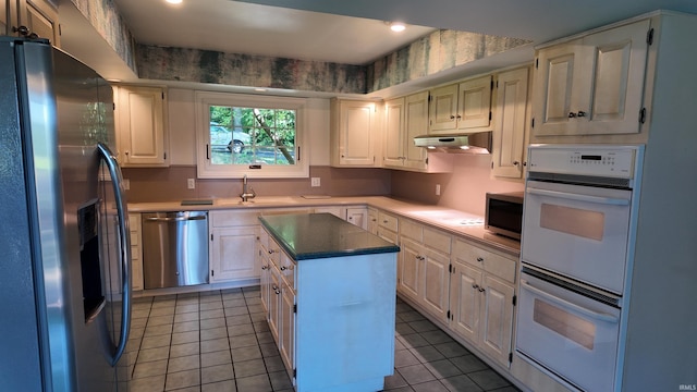 kitchen with light tile patterned floors, appliances with stainless steel finishes, sink, and a kitchen island