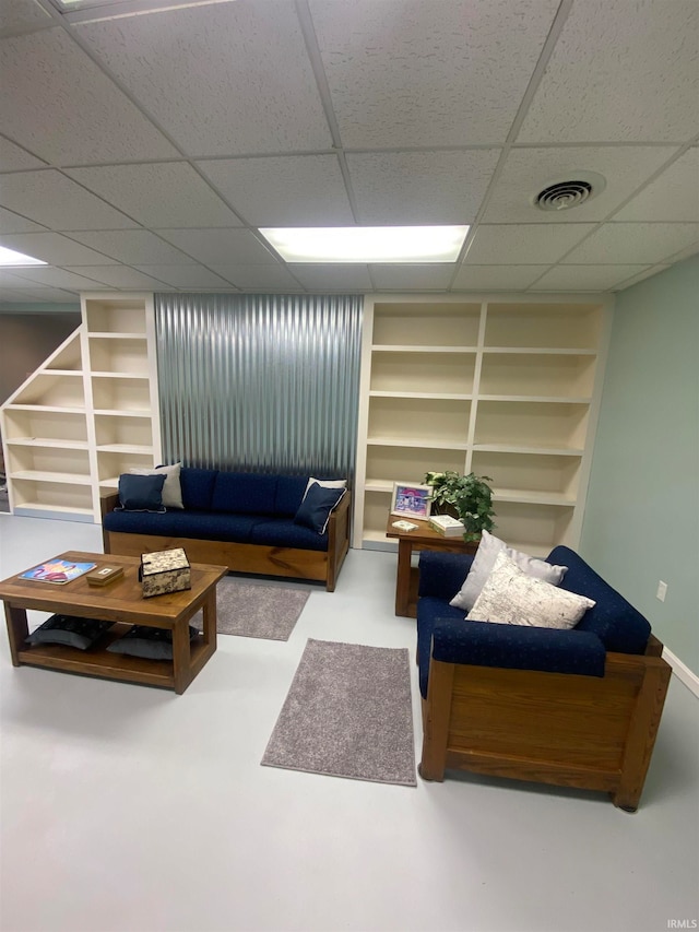 living room featuring built in features and a drop ceiling