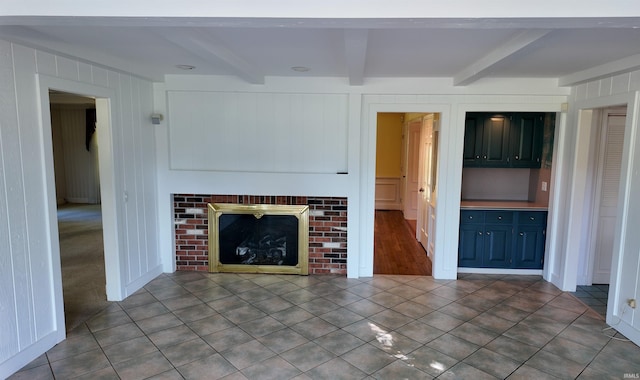 unfurnished living room with tile patterned flooring, a fireplace, and beamed ceiling