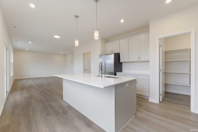 kitchen featuring a kitchen island with sink, stainless steel fridge with ice dispenser, light hardwood / wood-style floors, and white cabinets