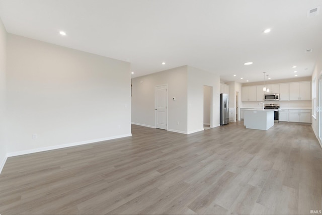 unfurnished living room with sink and light hardwood / wood-style flooring