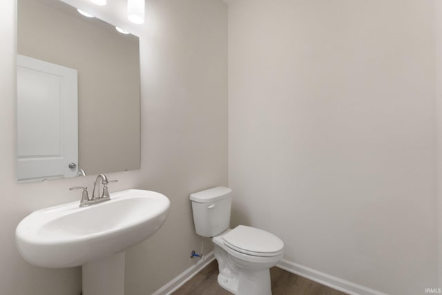 bathroom featuring toilet, sink, and hardwood / wood-style flooring