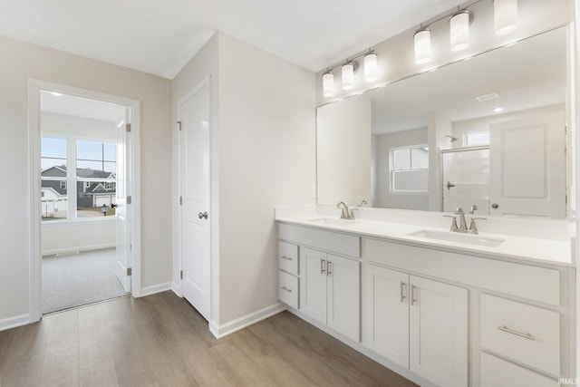 bathroom with hardwood / wood-style flooring, a shower with door, and vanity