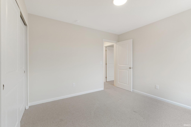 unfurnished bedroom with light colored carpet and a closet