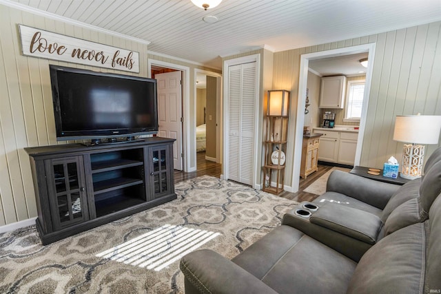 living room with wood walls, wood-type flooring, and crown molding