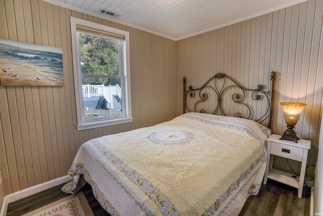 bedroom with wood walls, dark hardwood / wood-style flooring, and ornamental molding