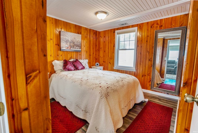 bedroom with wood walls and hardwood / wood-style floors