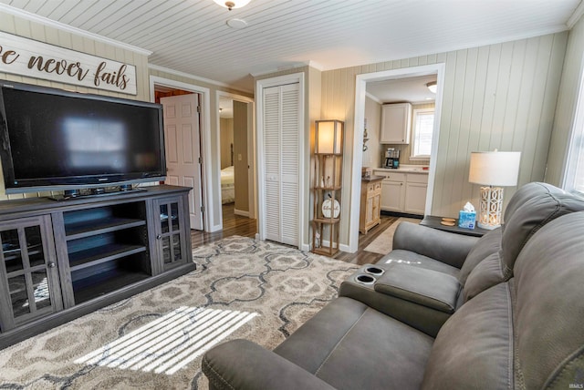 living room featuring ornamental molding, wood-type flooring, wood ceiling, and wood walls