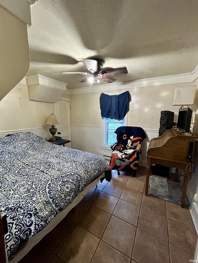 tiled bedroom featuring a textured ceiling, wainscoting, a ceiling fan, and ornamental molding