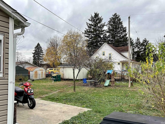 view of yard featuring a storage unit, an outdoor structure, a playground, and a patio