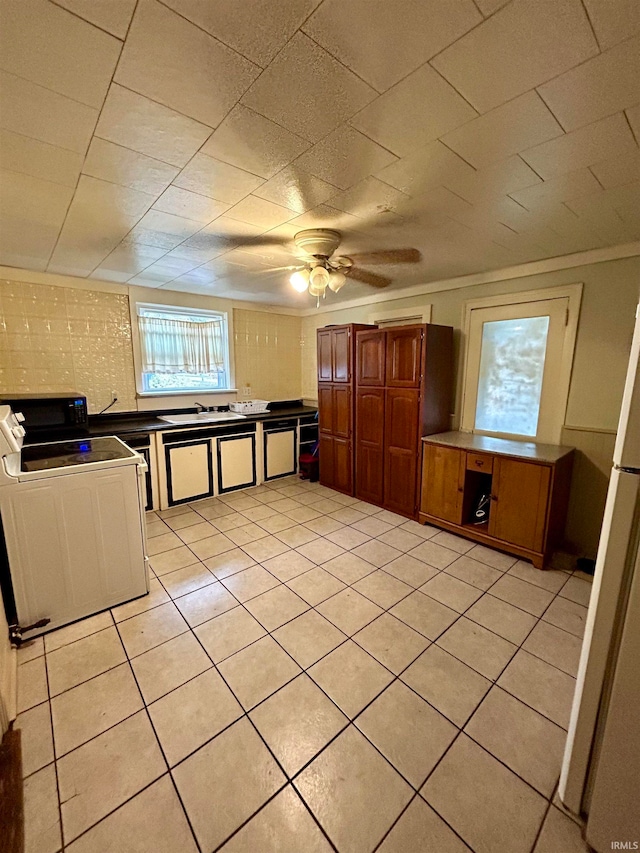 kitchen with ceiling fan, light tile patterned floors, crown molding, stove, and white refrigerator