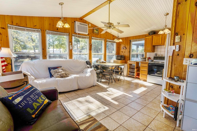 living room featuring wooden walls, vaulted ceiling, light tile patterned floors, and ceiling fan with notable chandelier