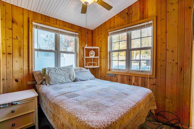 bedroom with wood walls, ceiling fan, multiple windows, and vaulted ceiling