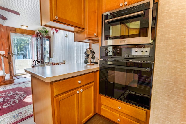 kitchen with black double oven, kitchen peninsula, and ceiling fan