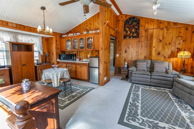 living room featuring wood walls, ceiling fan with notable chandelier, light colored carpet, and lofted ceiling