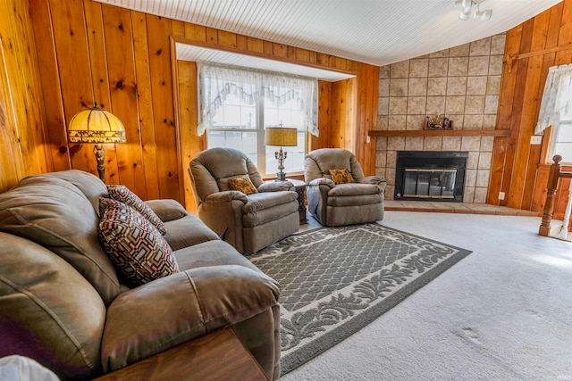 carpeted living room with a tiled fireplace, wood walls, and lofted ceiling