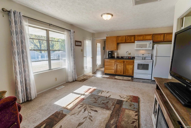 kitchen featuring white appliances, a textured ceiling, and light colored carpet