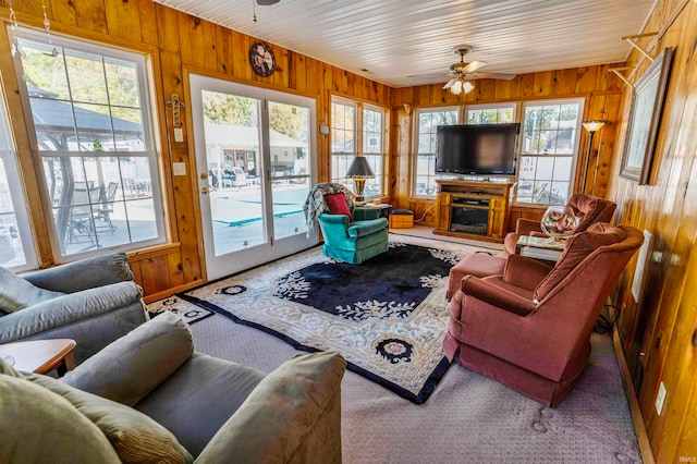 living room featuring wood walls, a healthy amount of sunlight, and ceiling fan