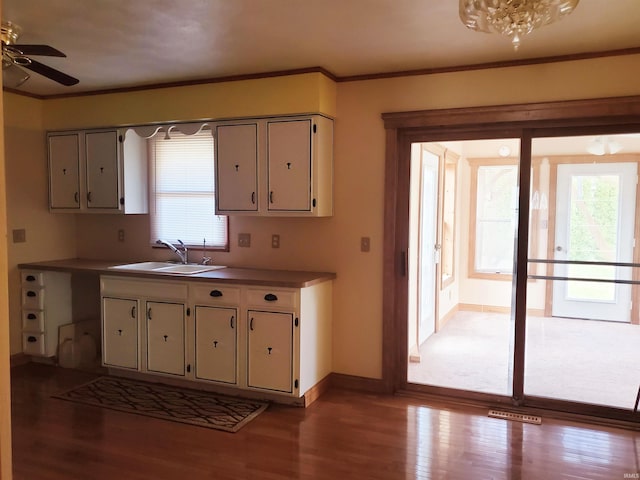 kitchen featuring light wood-type flooring, sink, ceiling fan, and crown molding