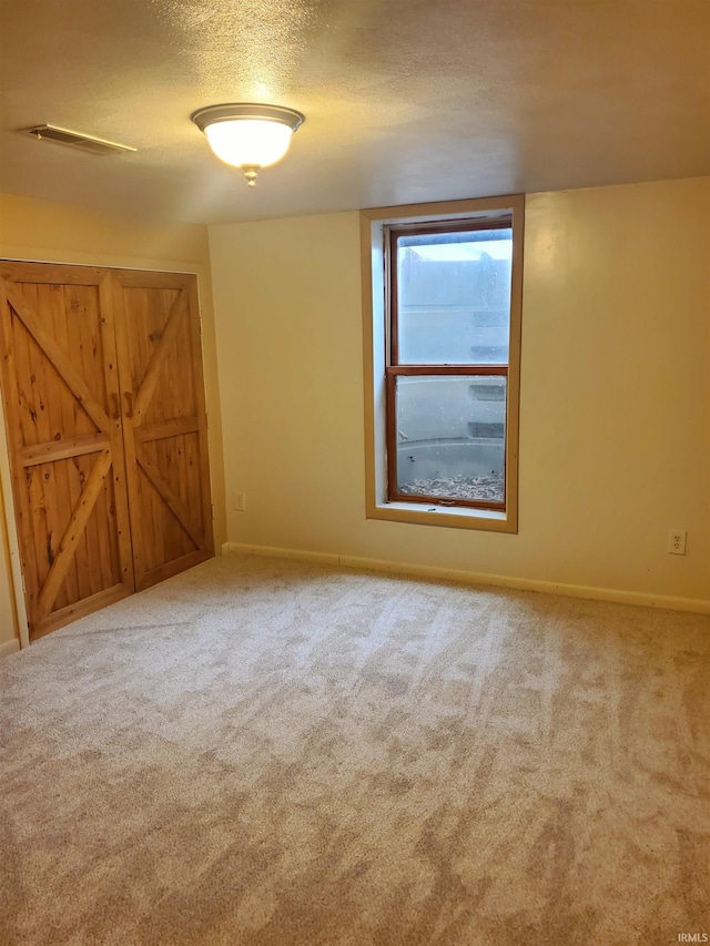 empty room with a textured ceiling and carpet flooring