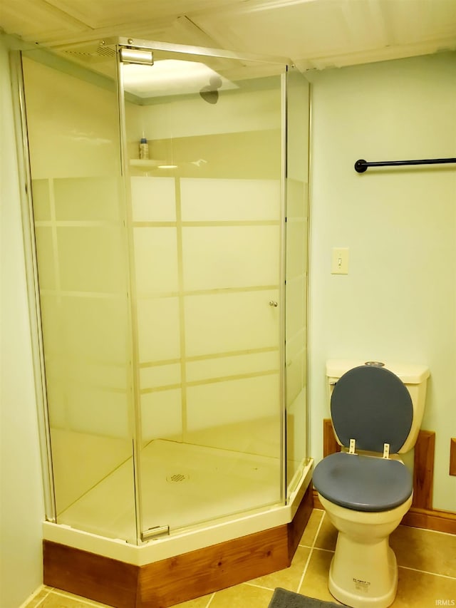 bathroom featuring toilet, tile patterned floors, and a shower with door