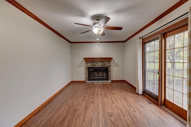 unfurnished living room featuring a brick fireplace, light wood-type flooring, ceiling fan, and crown molding