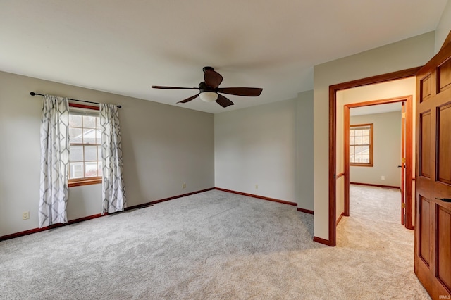 empty room with light carpet, a healthy amount of sunlight, and ceiling fan