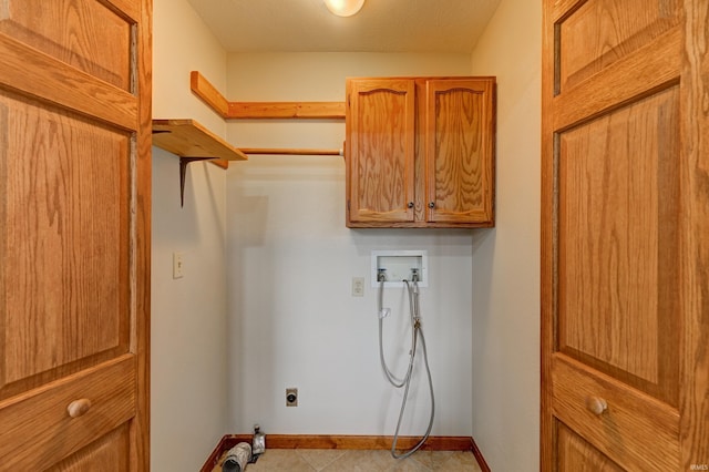 washroom with electric dryer hookup, washer hookup, cabinets, and a textured ceiling