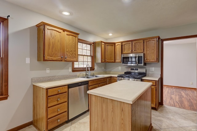 kitchen with stainless steel appliances, sink, a kitchen island, and light tile patterned floors